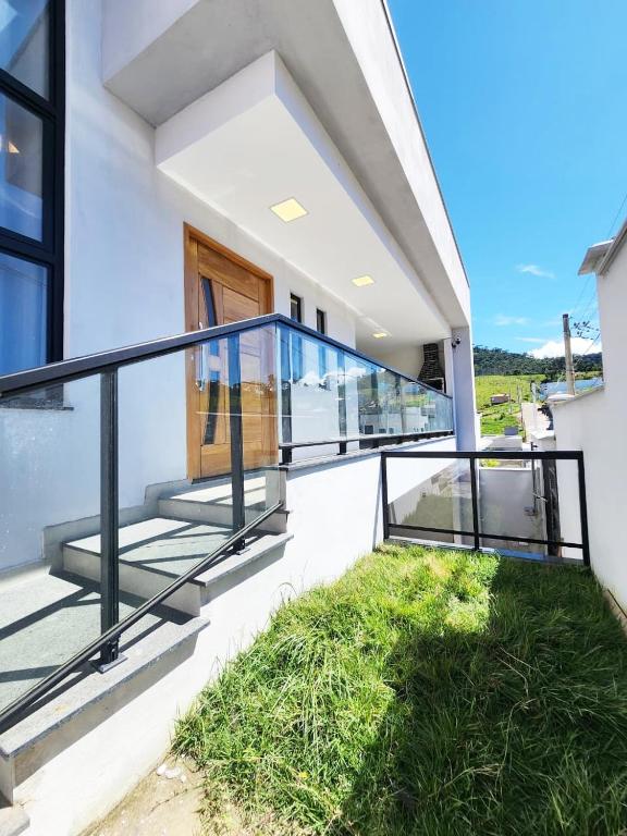 a balcony of a house with glass railings and grass at Casa para 4 pessoas I Churrasqueira I Garagem para 2 carros I 5min do centro in São Lourenço