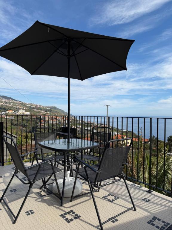 a table and chairs with an umbrella on a balcony at Casa da Quinta in Estreito da Calheta