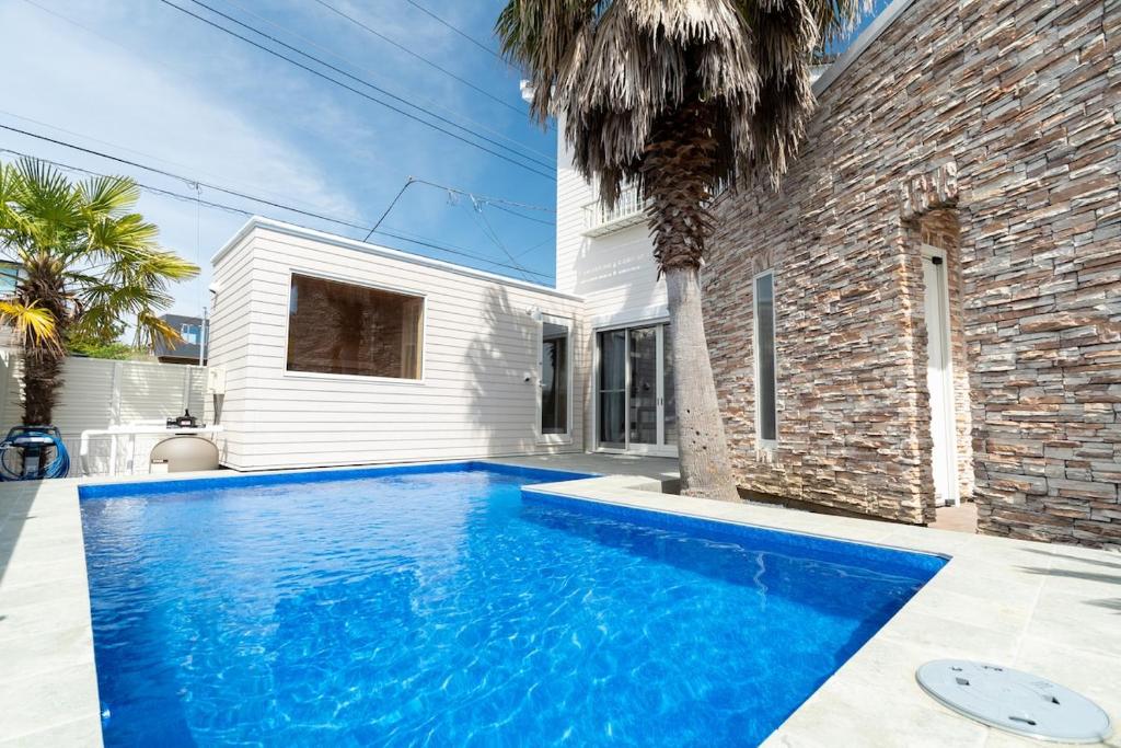 a large blue swimming pool in front of a house at Seasiders in Ichinomiya