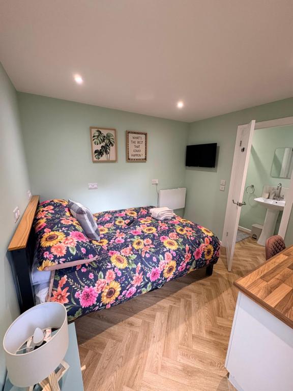 a bedroom with a bed with a floral bedspread at Clover Road Guest Suite in Swaffham