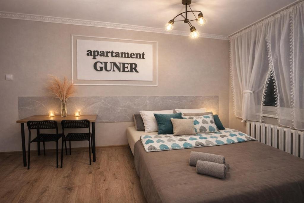 a bedroom with a bed and a desk and a table at GUNER Apartament Bełchatów in Bełchatów