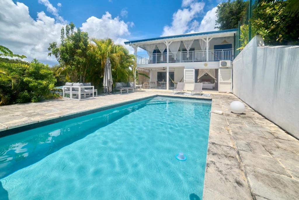 a swimming pool in front of a house at villa vue mer logements indépendants piscine privative in Grand-Bourg