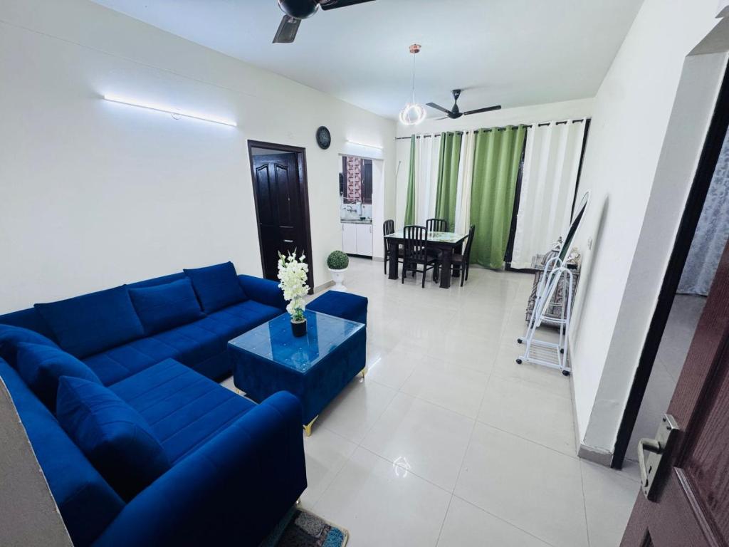 a living room with a blue couch and a table at Homely stayy in Mohali