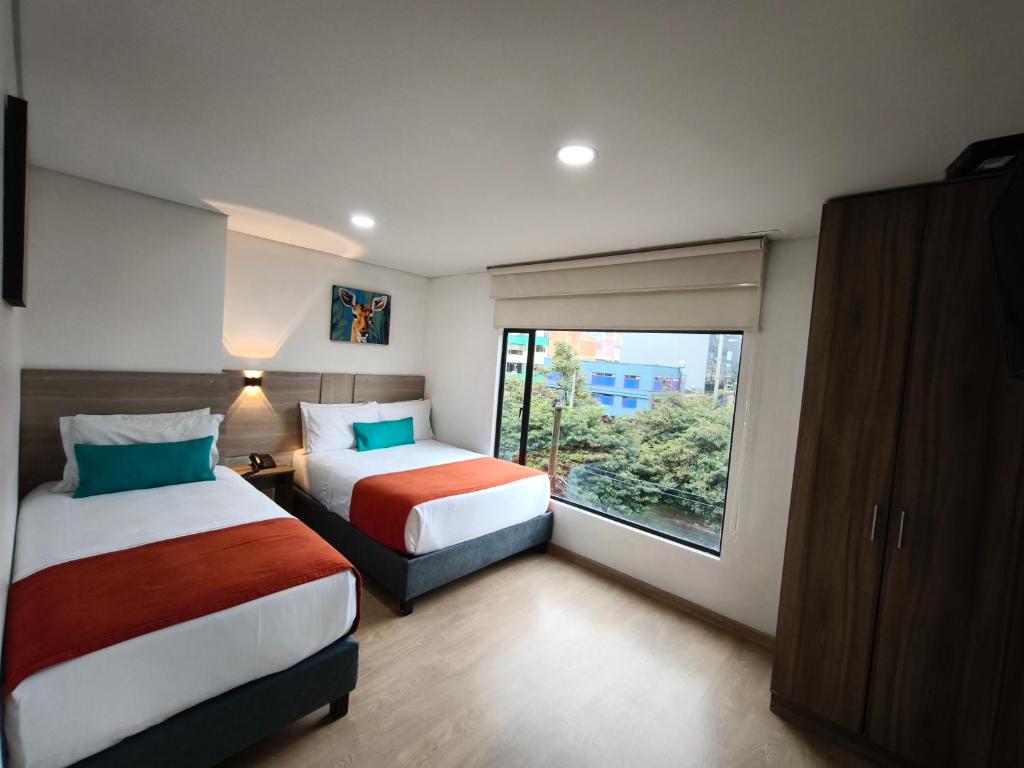 a hotel room with two beds and a window at Hotel Portal de los Andes in Bogotá
