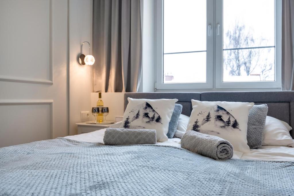 a bedroom with a bed with pillows and a window at Apartamenty Centrum 50 m od Rynku, FREE PARKING in Nowy Targ