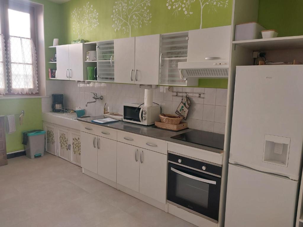 a kitchen with white cabinets and a white refrigerator at Jolie maison de Potier in Accolay