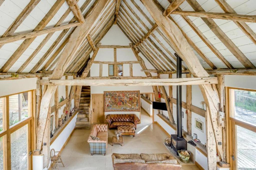 a large living room with wooden ceilings and windows at Unique Luxury Barn in Tenbury