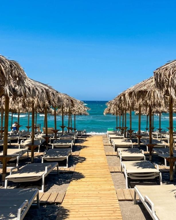 a row of chairs and umbrellas on a beach at Lotus Serenity Suites in Amoudara Herakliou