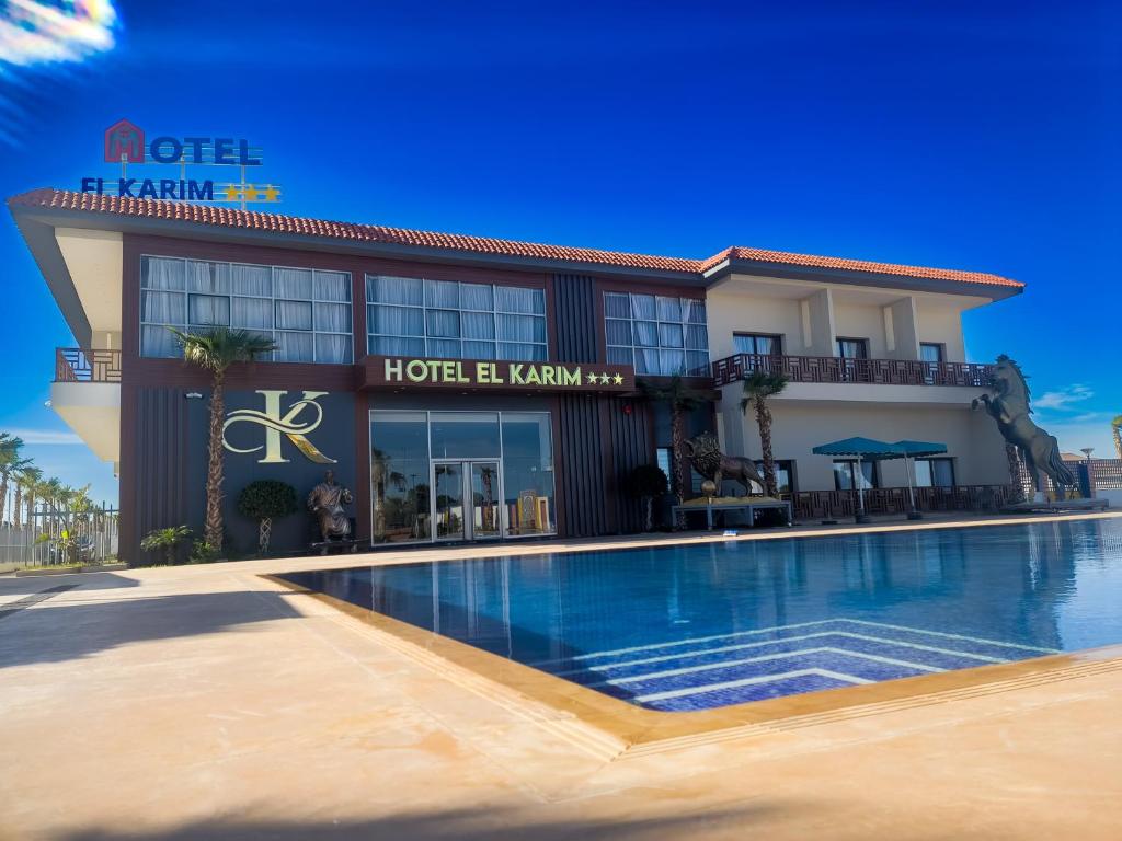 ein Hotel mit einem Schwimmbad vor einem Gebäude in der Unterkunft Hotel El Karim in Oujda