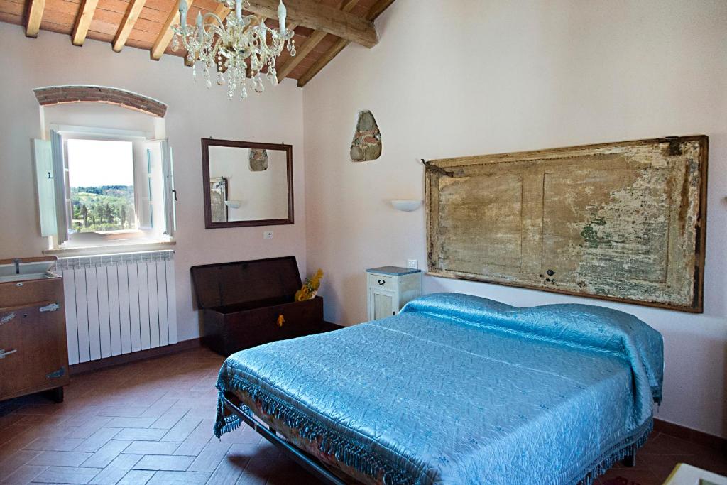 1 dormitorio con cama, ventana y lámpara de araña en Agriturismo L'isola, en Crespina