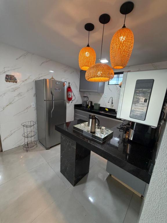 a kitchen with a black counter and a refrigerator at Chalé Dona Ceci in Cavalcante