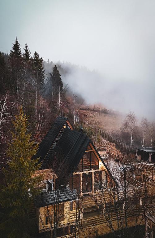 a log cabin in the woods with fog in the background at Black Roof in Arada