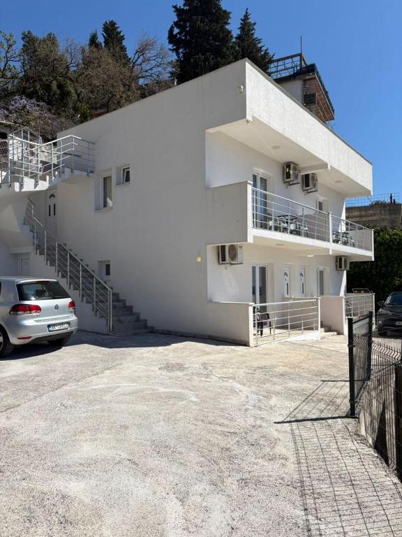 a white building with a car parked in front of it at Apartments Sole 2 in Sutomore