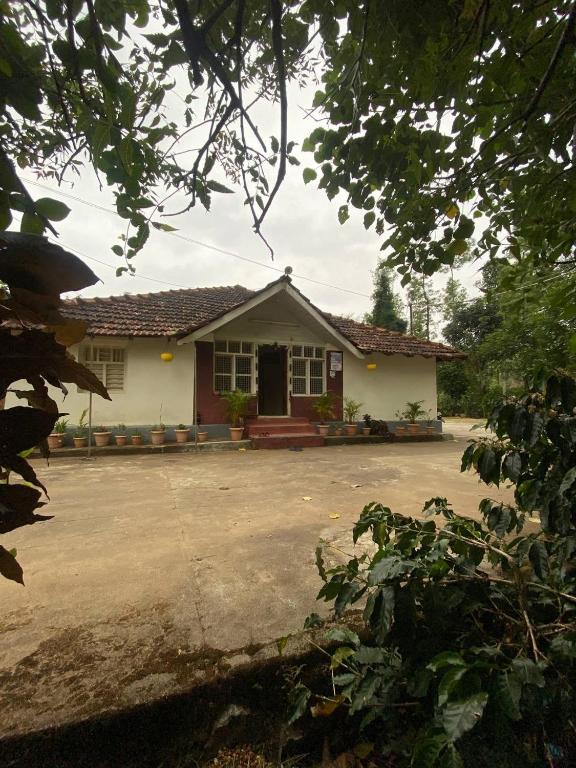 a small white house with a driveway in front of it at Gope town mudigere in Mudigere
