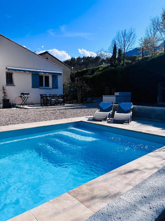 a swimming pool with two chairs and a house at Private riverside villa with breathtaking views in Axat