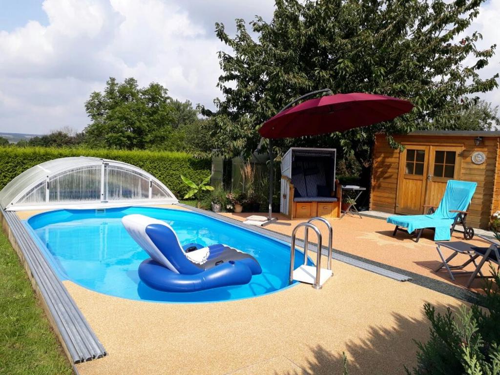 a small swimming pool with an umbrella and a blue inflatable at Ferienwohnung Schulrath in Eichwerder
