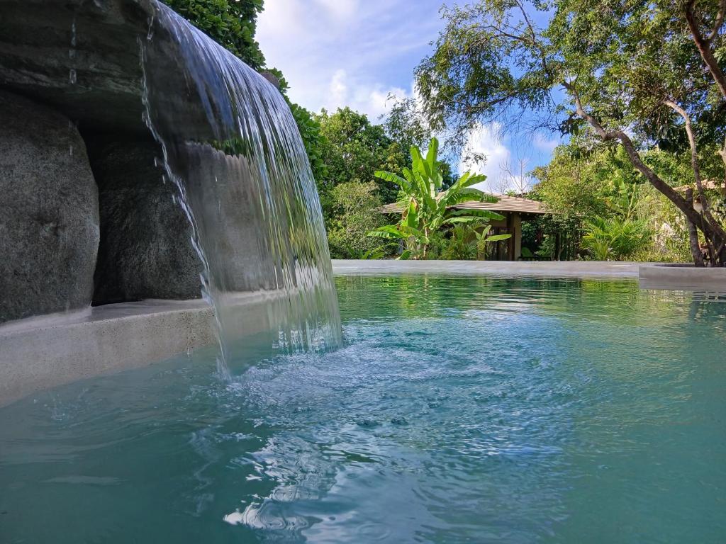 a waterfall in the middle of a pool of water at Vila Natholi Hotel Boutique in Imbassai