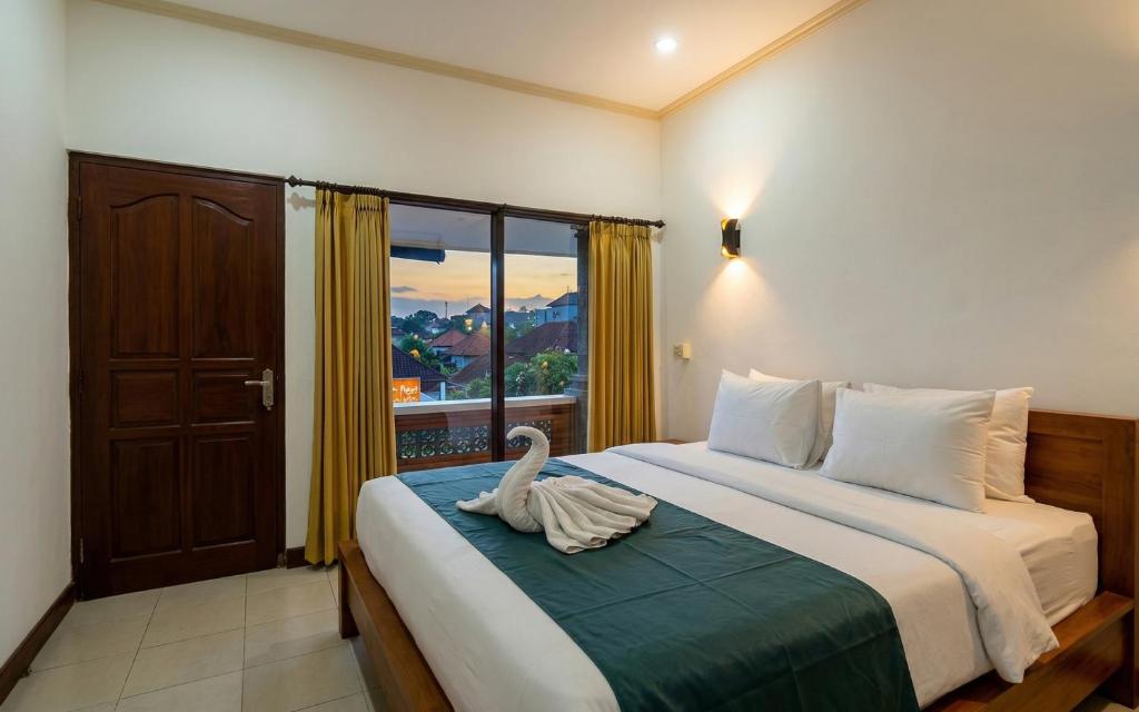 a bedroom with a bed with a swan on it at Rumah Rini by Rumah Weda in Ubud