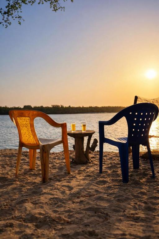 two chairs and a table on the beach with the sunset at Campement Clair de Lune - Chez Dam et Amcé in Kachiouane
