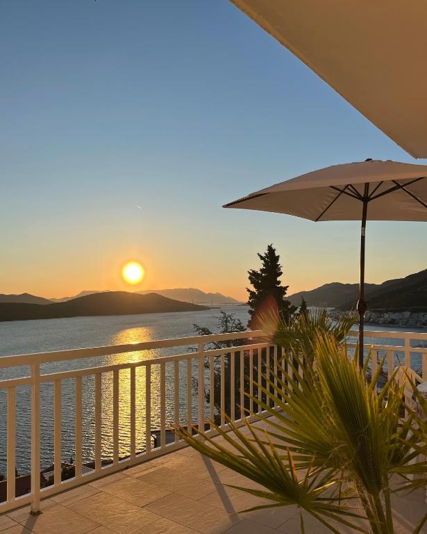a sunset on a balcony with an umbrella at Guest House Life in Neum