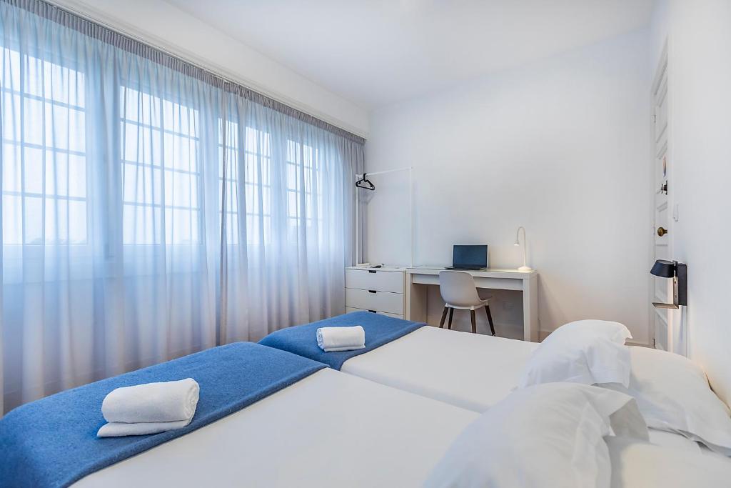 a bedroom with two beds and a desk and a window at HI Coimbra - Pousada de Juventude in Coimbra