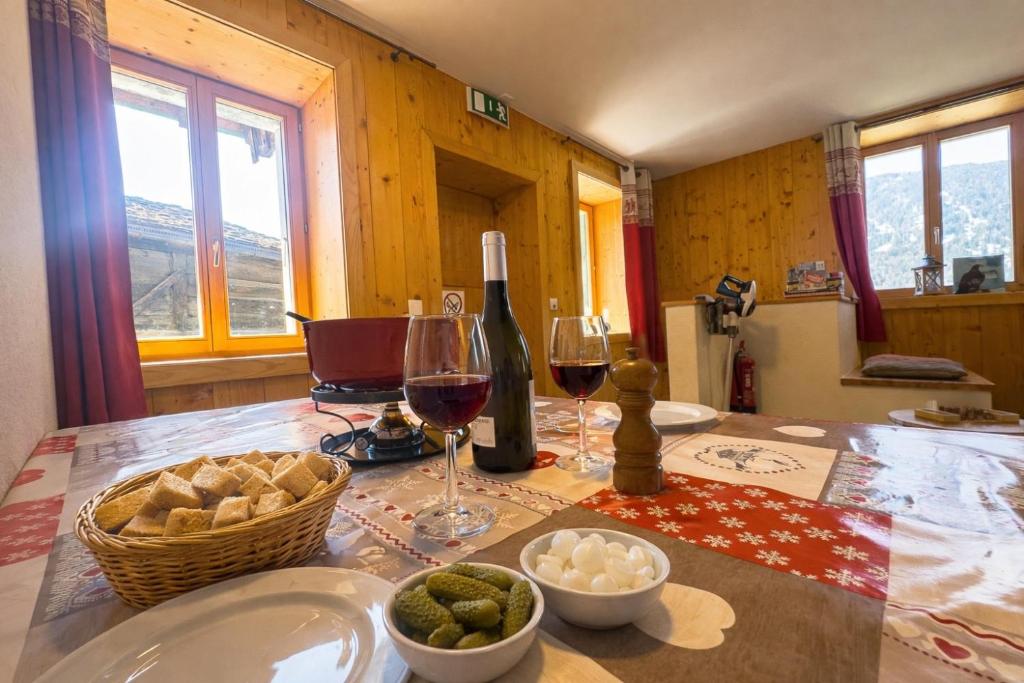 a table with two glasses of wine and a basket of food at Gîte de chandonne in Liddes