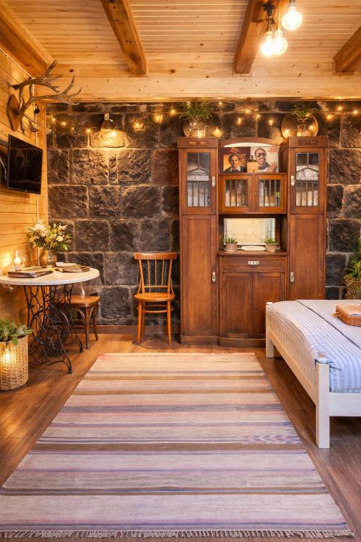 a bedroom with a bed and a table and a stone wall at Alashkert Guesthouse Premium and Cozy Studios in Gyumri in Gyumri