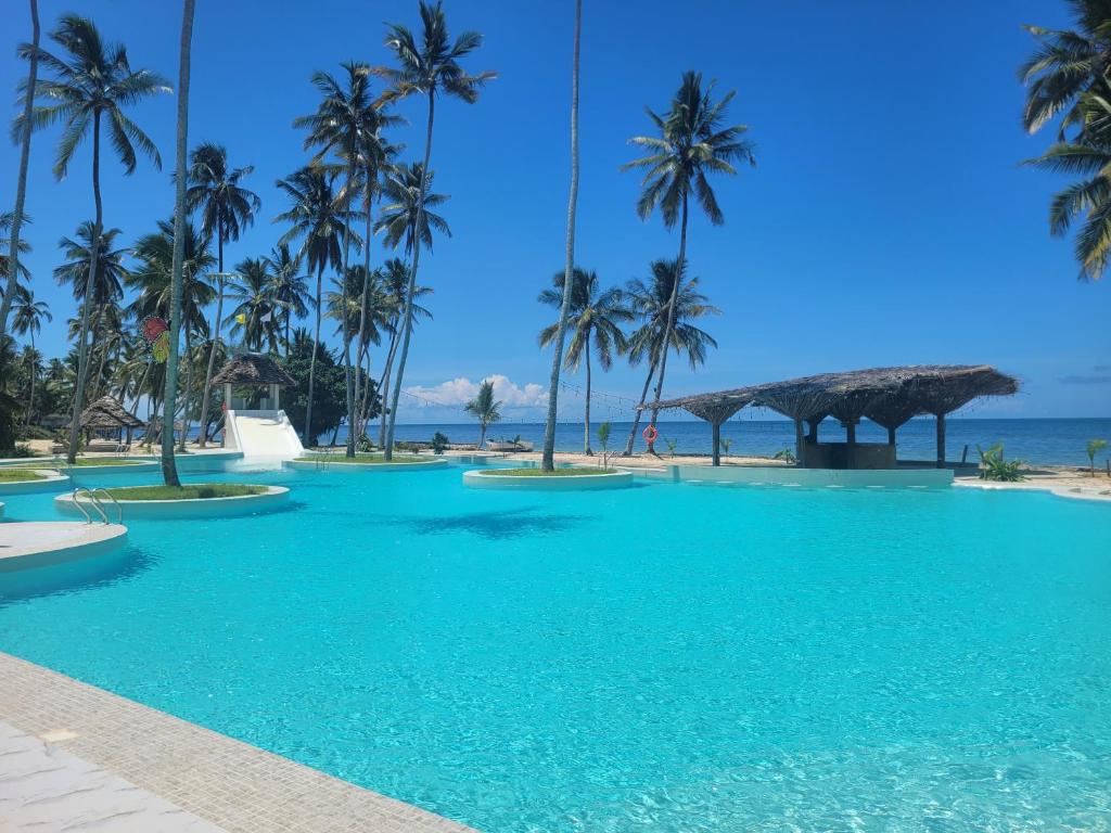 a swimming pool with palm trees on the beach at Antonio Beach in Uroa