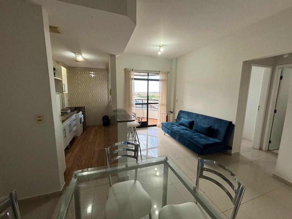 a living room with a blue couch and a table at Flat Jardim de Allah in Campos dos Goytacazes