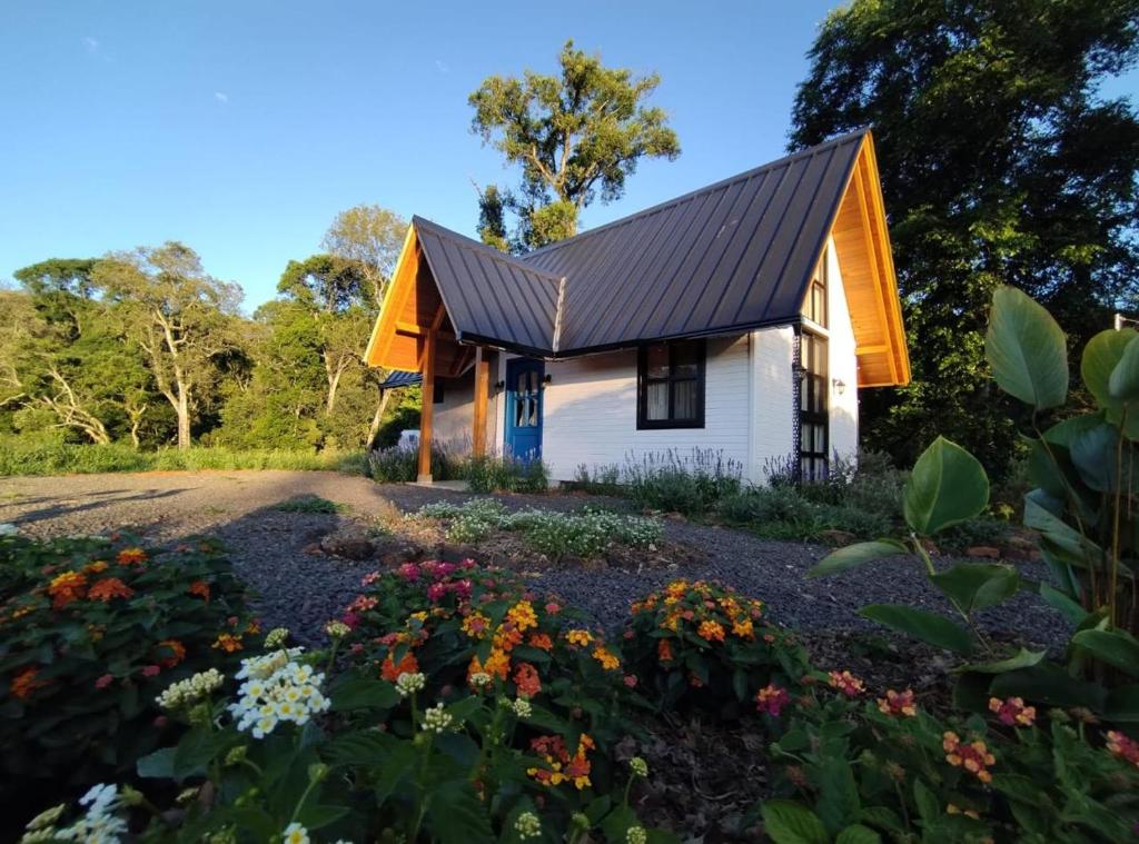 a small white house with an orange roof and flowers at Cabana Vale das Bromélias in Videira