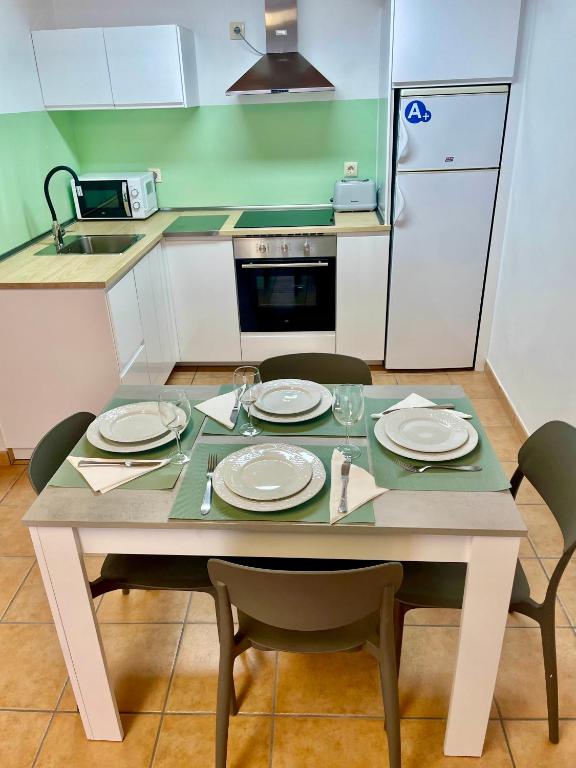 a small kitchen with a table with plates and chairs at Puertoplaya 2 in Malpica