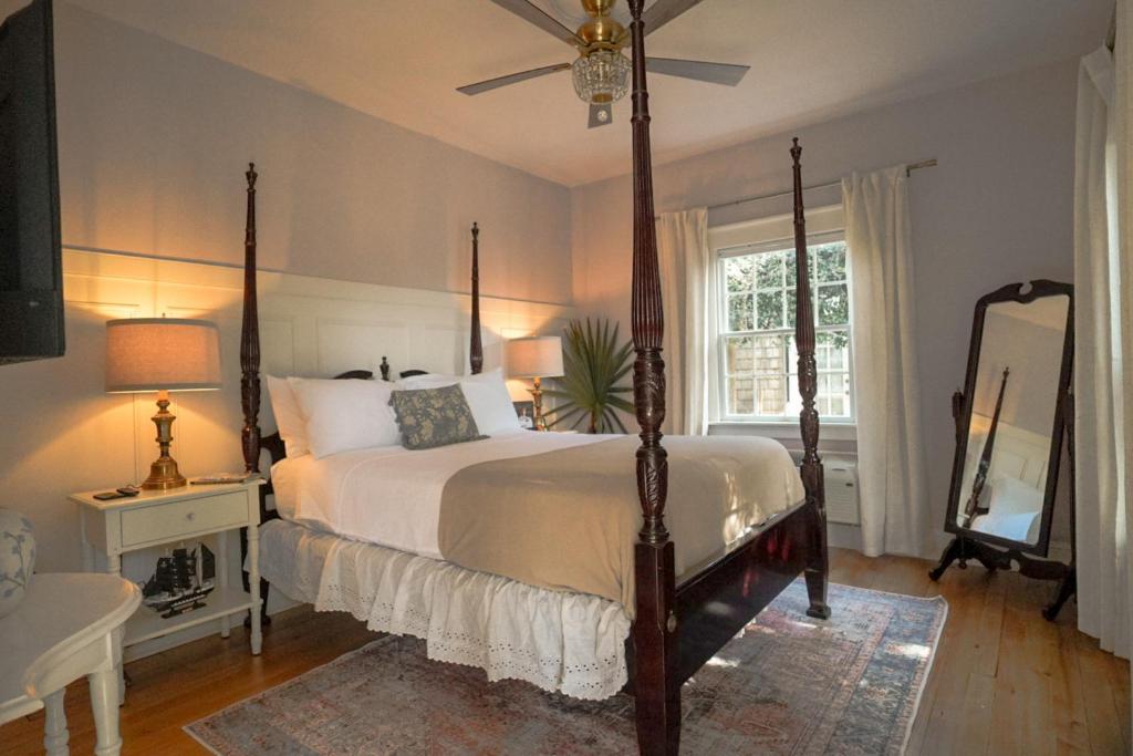 a bedroom with a canopy bed and a mirror at Thurston House Inn in Ocracoke