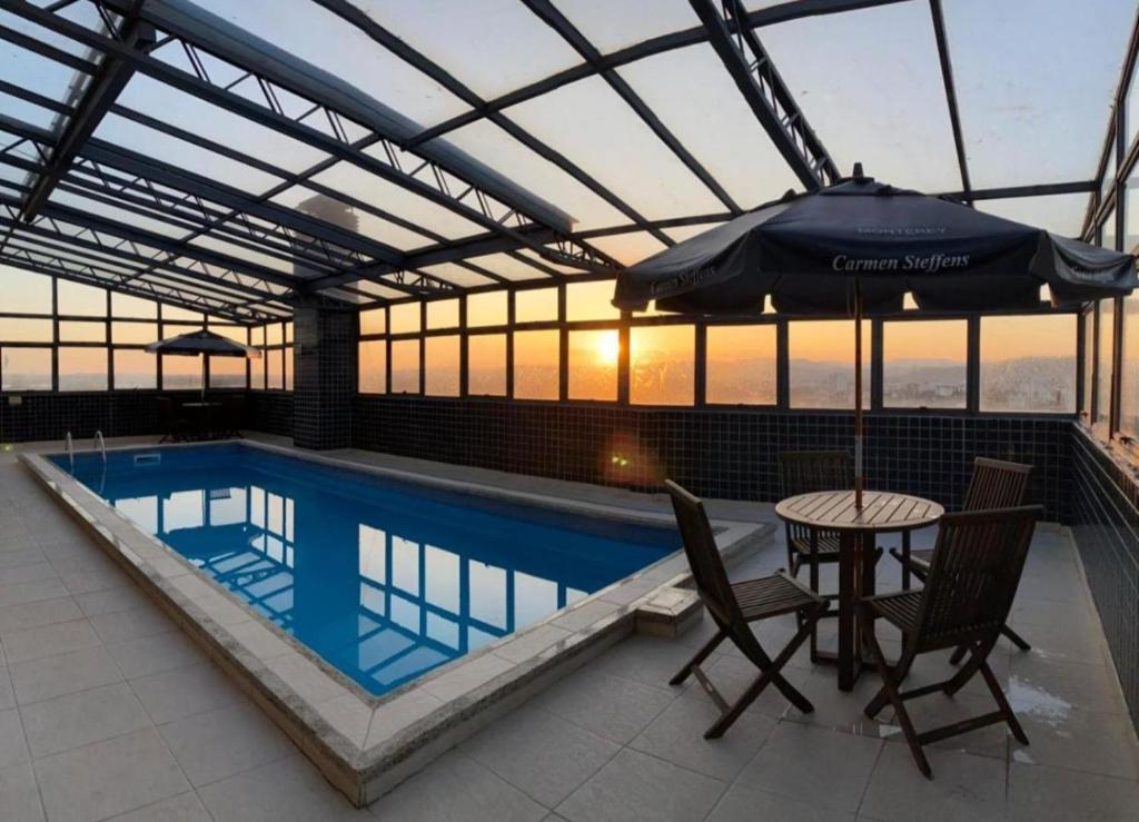 a swimming pool with an umbrella and a table and chairs at Aquarius Flat 510 in Santa Cruz do Sul