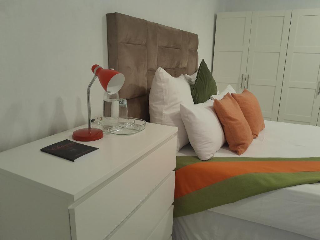 a bed with a table with a lamp on it at Borrowdale Top End - Apartments in Harare