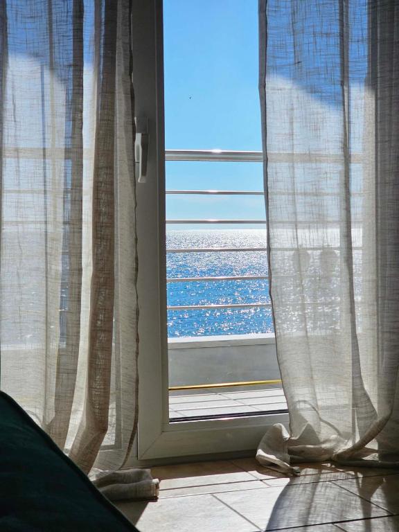 a window with a view of the ocean through it at Seaside Stay Makrygialos in Makrygialos