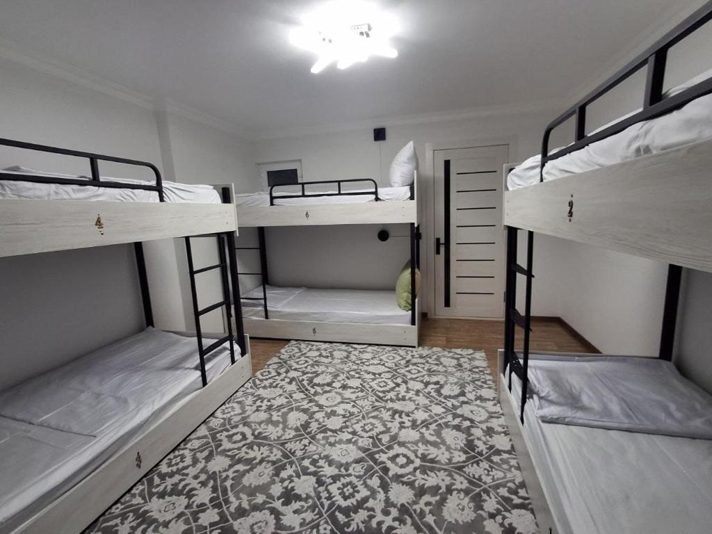 a room with three bunk beds and a rug at BridgeStayHostel in Samarkand