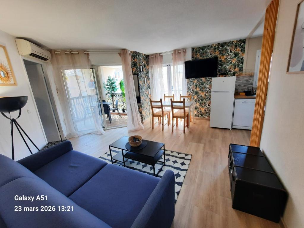 a living room with a blue couch and a kitchen at Coeur Marina climatisé terrasse parking in Fréjus