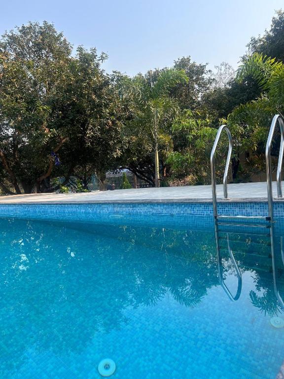 a swimming pool with blue water and trees at Nadaa Organic Farms in Khammam
