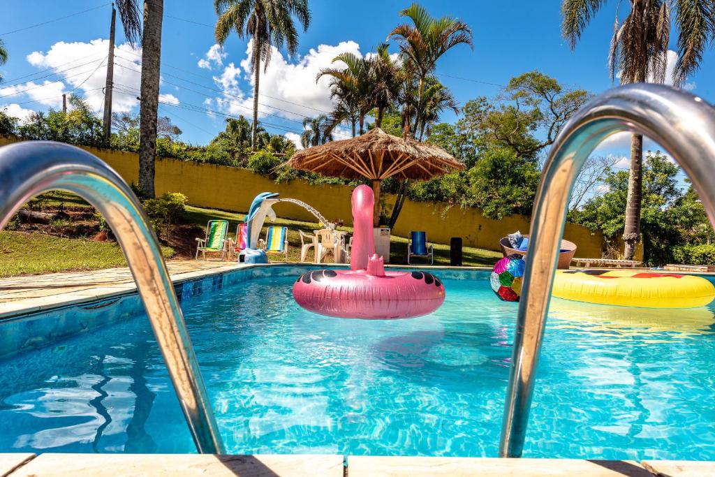 a swimming pool with an umbrella and some water slides at Paraíso com Piscina, Churrasqueira, Wi-Fi e Karaokê in Ibiúna