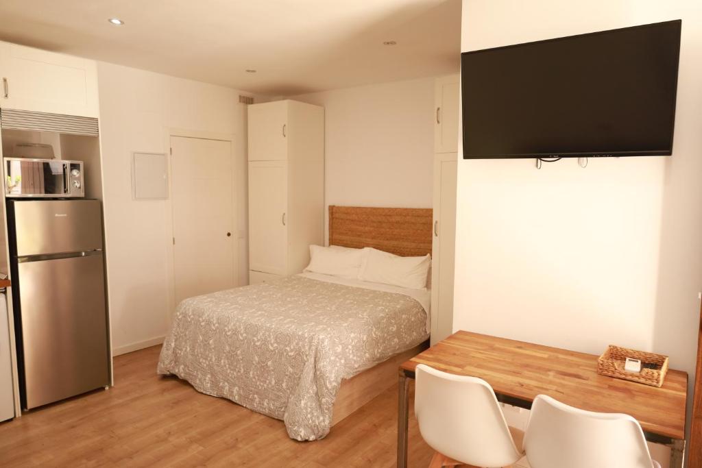 a bedroom with a bed and a table and a refrigerator at Estudio a 400 metros Ribera FREE PARKING in Córdoba