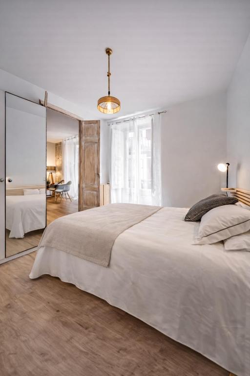 a white bedroom with a large bed and a mirror at 22CaLQuEROL Boutique centro suite lux in Puigcerdà