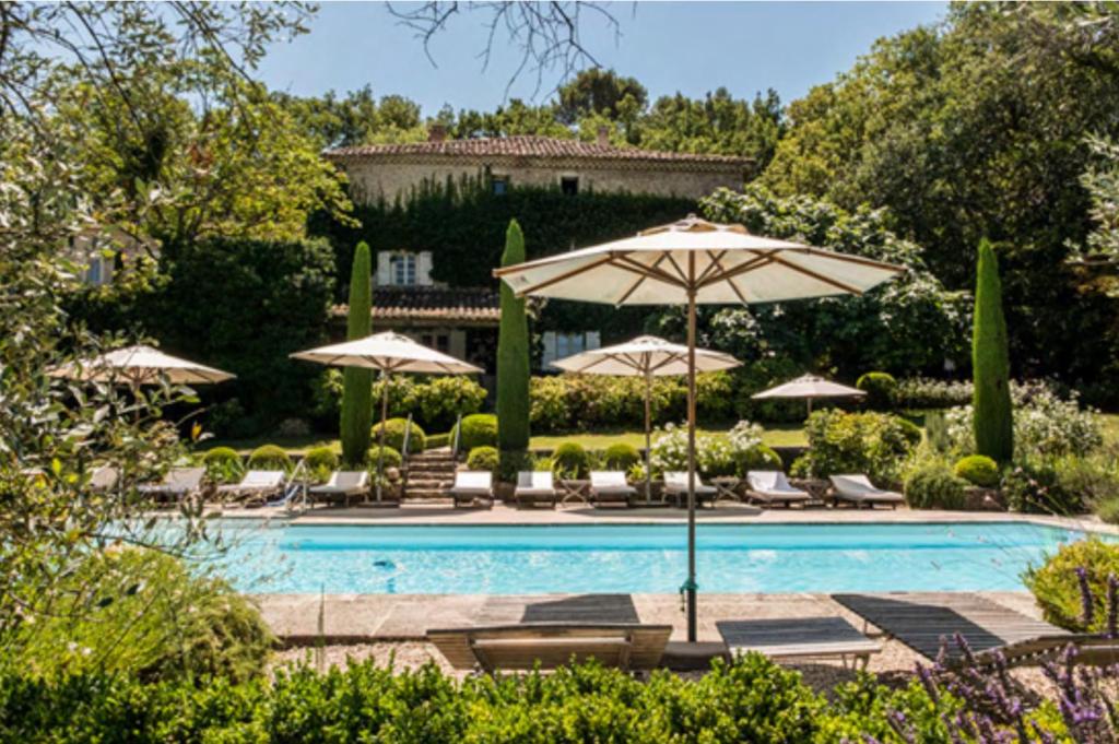 a swimming pool with umbrellas and lounge chairs and a pool at La Ribaude in Crestet