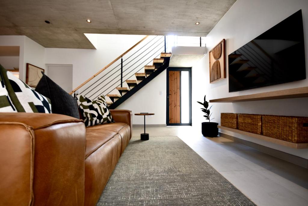 a living room with a couch and a tv and stairs at Rustic Hills 39 in Swakopmund