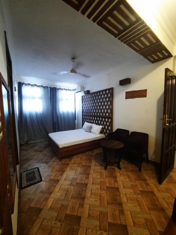 a bedroom with a bed and a table in a room at Kuti Hotel Stone Town in Ngambo