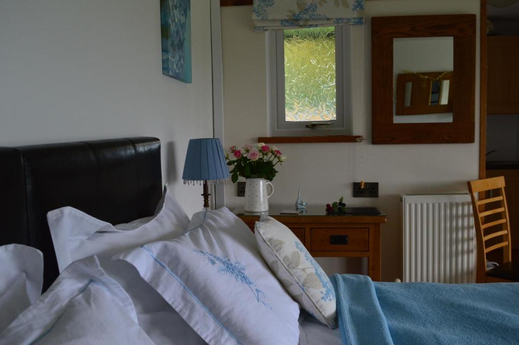 ein Schlafzimmer mit einem Bett mit weißen Kissen und einem Fenster in der Unterkunft Smithfield Farm Bed & Breakfast in Builth Wells