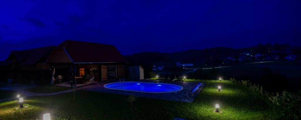 a backyard with a swimming pool at night at Holiday Home BIBA With Heated Outdoor Pool in Gornja Stubica