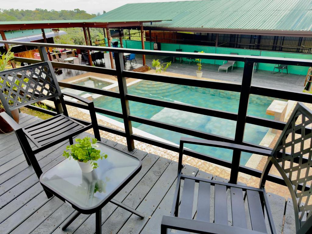 a balcony with two chairs and a table and a pool at Paulos View Lodge in Colonia