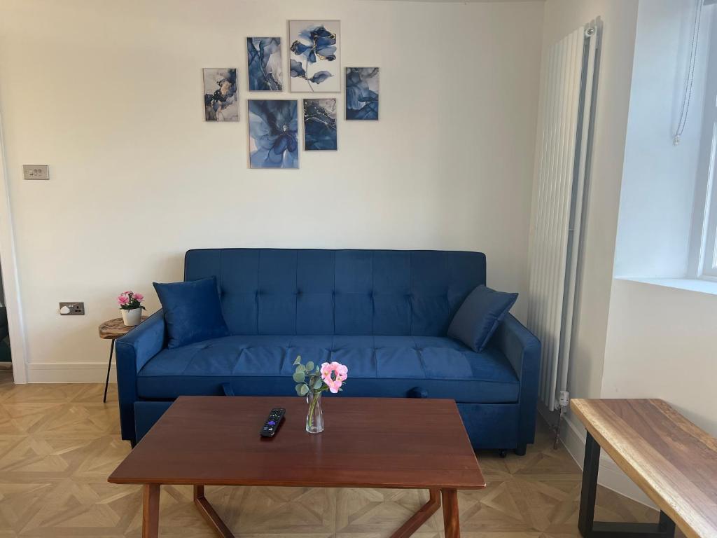 a blue couch in a living room with a table at Luxury 4BR Bungalow in Hackbridge