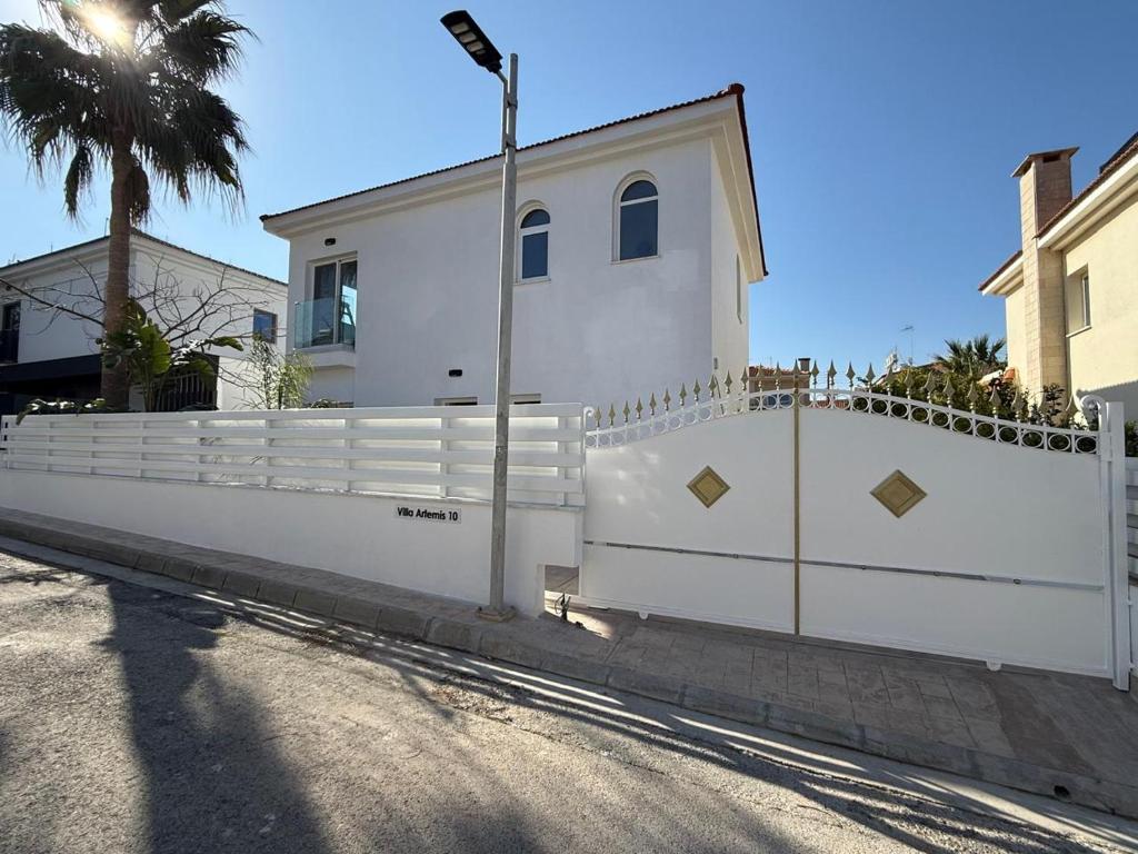 a white fence in front of a house at Villa Artemis - 150m from Kapparis Beach in Paralimni