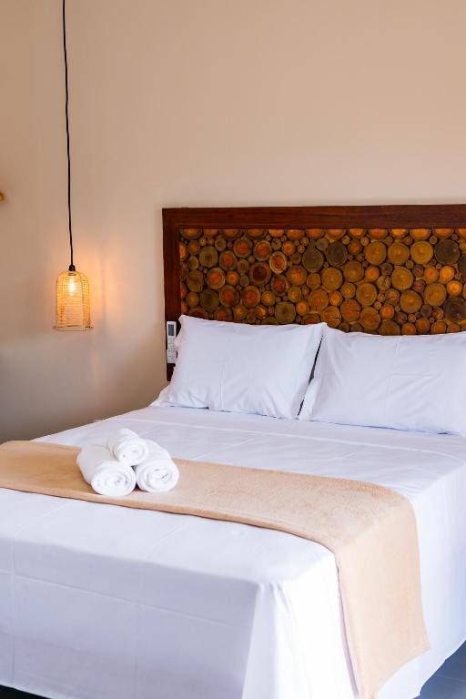a bedroom with a bed with two towels on it at Pousada Brisa do Cardeiro in São Miguel do Gostoso